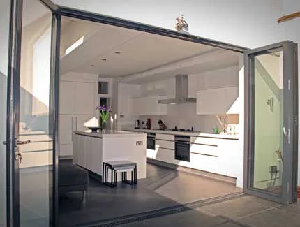 Grey aluminium bifold doors opening from a kitchen