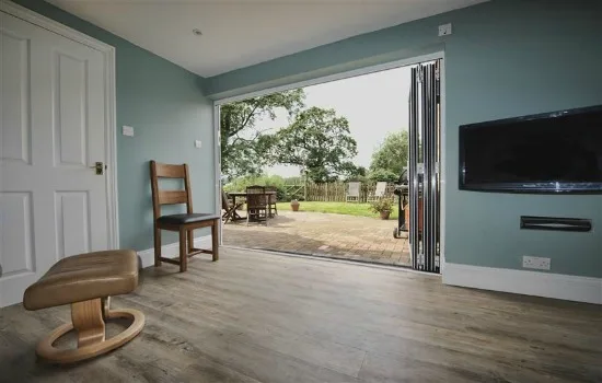 Teal-painted living room with bifold doors open onto the garden