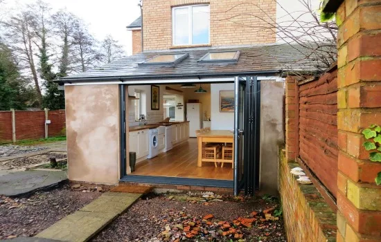 Grey bifold doors open on a small rear extension, with the kitchen visible inside