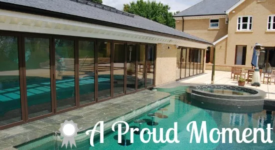 Bifold doors along a poolside room overlooking an outdoor swimming pool