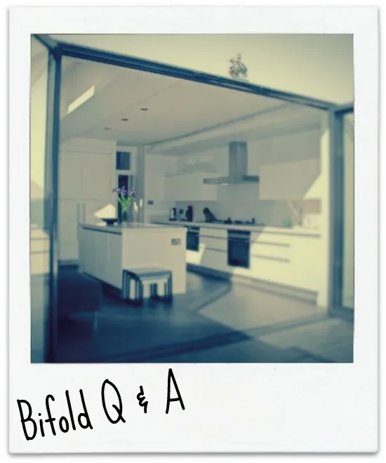 Polaroid-style photo of a white kitchen seen through open bifold doors