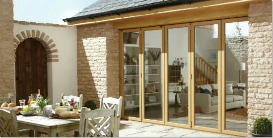 Timber bifold doors on a stone barn conversion, with an outdoor dining table alongside