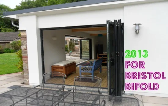 Black bifold doors open on a garden room leading onto a paved terrace