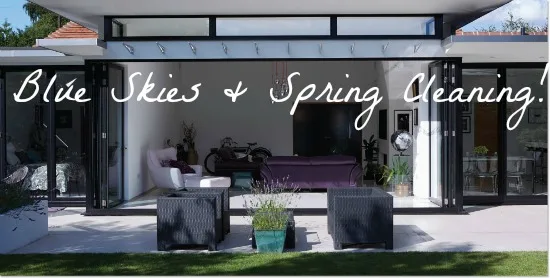 Dark bifold doors open across the rear of a modern house onto a lawn