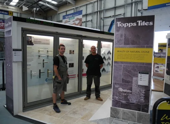 Two Bristol Bifold staff beside the company's door display stand at the NSBRC in Swindon